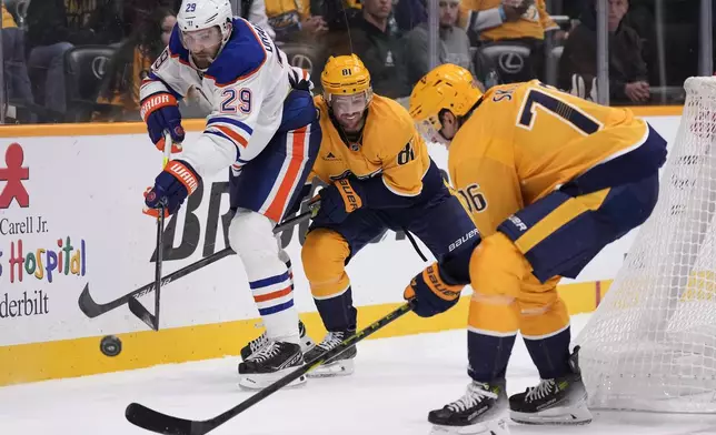 Edmonton Oilers center Leon Draisaitl (29) passes the puck past Nashville Predators center Jonathan Marchessault (81) and defenseman Brady Skjei (76) during the third period of an NHL hockey game Thursday, Oct. 17, 2024, in Nashville, Tenn. (AP Photo/George Walker IV)