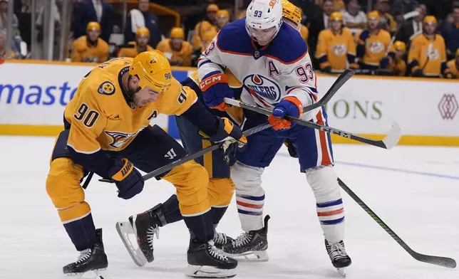 Nashville Predators center Ryan O'Reilly (90) and Edmonton Oilers center Ryan Nugent-Hopkins (93) vie for the puck during the second period of an NHL hockey game Thursday, Oct. 17, 2024, in Nashville, Tenn. (AP Photo/George Walker IV)