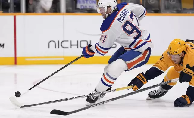 Edmonton Oilers center Connor McDavid (97) shoots the puck past Nashville Predators defenseman Jeremy Lauzon (3) during the first period of an NHL hockey game Thursday, Oct. 17, 2024, in Nashville, Tenn. (AP Photo/George Walker IV)