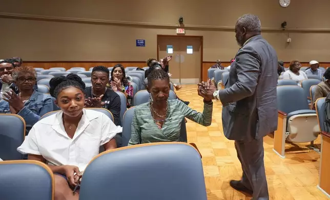 Sundiata Haley, son of Oretha Castle Haley, is congratulated by civil rights attorney Tracy L. Washington, as he walks to his seat after speaking during a city council hearing regarding the dispute over Oretha Castle Haley's former home, and plans by others to create a museum, in New Orleans, Thursday, Oct. 24, 2024. (AP Photo/Gerald Herbert)