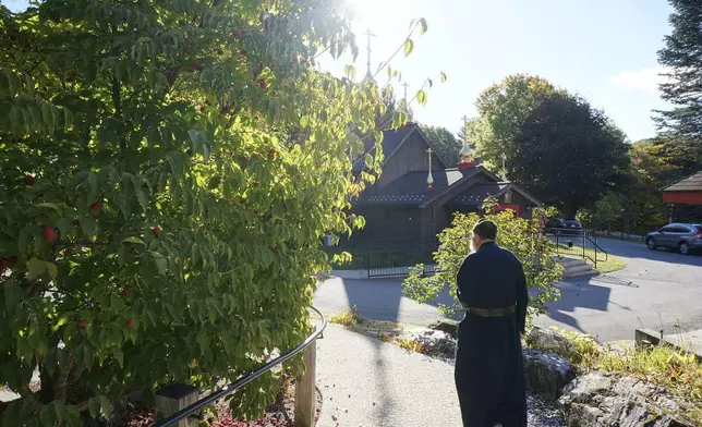 Brother Luke, an Orthodox Christian monk, walks toward the Church of Holy Transfiguration, the first church built by the brothers in 1970 for the New Skete monastery, which runs both a dog breeding and a dog training program outside Cambridge, N.Y., on Oct. 12, 2024. (AP Photo/Giovanna Dell’Orto)