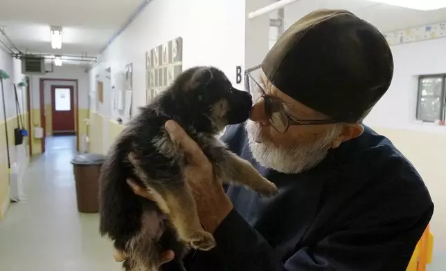 Brother Luke, an Orthodox Christian monk, holds a five-week-old German shepherd puppy from the latest litter in the dog breeding program that for decades has provided both financial and spiritual support to the New Skete monastery outside Cambridge, N.Y., on Oct. 12, 2024. (AP Photo/Giovanna Dell’Orto)