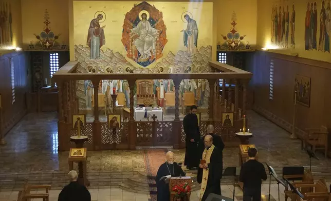 Brother Marc, center, one of the founders of the Orthodox Christian community of New Skete, and its current prior, Brother Christopher, right, holding book, finish morning prayers in the Church of Holy Wisdom, the larger of two churches of the monastery renowned for dog breeding and training programs outside Cambridge, N.Y., on Oct. 12, 2024. (AP Photo/Giovanna Dell’Orto)