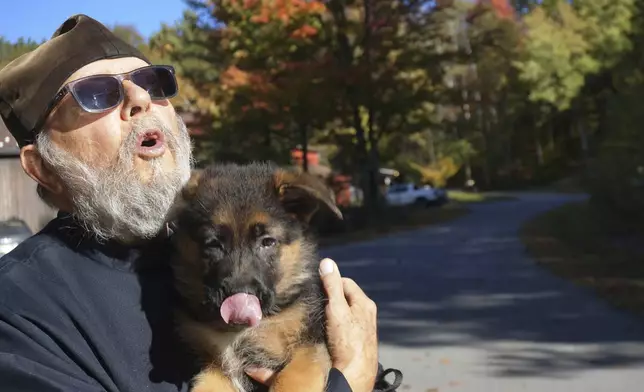 Brother Luke, an Orthodox Christian monk, holds his 10-week-old German shepherd Pyrena on the grounds of the New Skete monastery, where he directs the dog breeding program that has provided both financial and spiritual support to the community for decades outside Cambridge, N.Y., on Oct. 12, 2024. (AP Photo/Giovanna Dell’Orto)