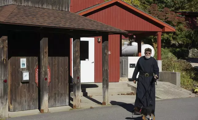 Brother Luke, an Orthodox Christian monk, walks his 10-week-old German shepherd Pyrena outside the residences of the New Skete monastery, where he directs the dog breeding program that has provided both financial and spiritual support to the community for decades outside Cambridge, N.Y., on Oct. 12, 2024. (AP Photo/Giovanna Dell’Orto)