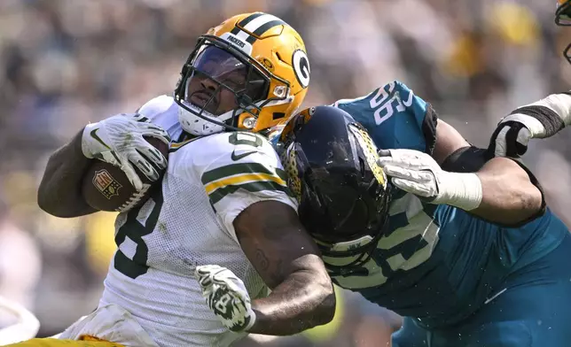 Jacksonville Jaguars' Jeremiah Ledbetter stops Green Bay Packers' Josh Jacobs during the second half of an NFL football game Sunday, Oct. 27, 2024, in Jacksonville, Fla. (AP Photo/Phelan M. Ebenhack)