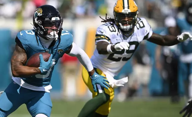 Jacksonville Jaguars' Christian Kirk runs past Green Bay Packers' Xavier McKinney after a catch during the first half of an NFL football game Sunday, Oct. 27, 2024, in Jacksonville, Fla. (AP Photo/Phelan M. Ebenhack)