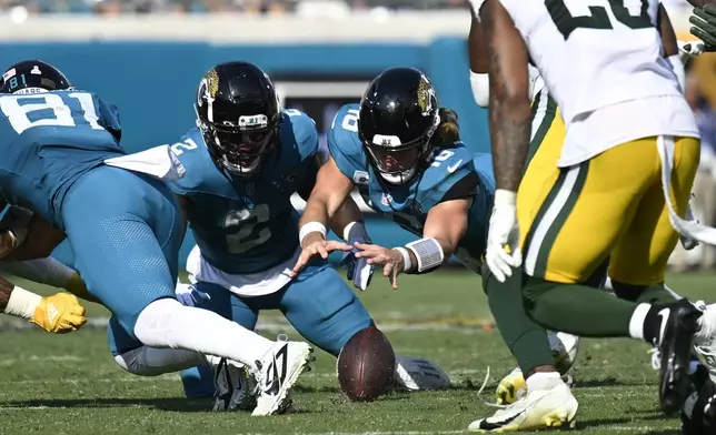 Jacksonville Jaguars' Trevor Lawrence recovers his own fumble during the second half of an NFL football game against the Green Bay Packers Sunday, Oct. 27, 2024, in Jacksonville, Fla. (AP Photo/Phelan M. Ebenhack)