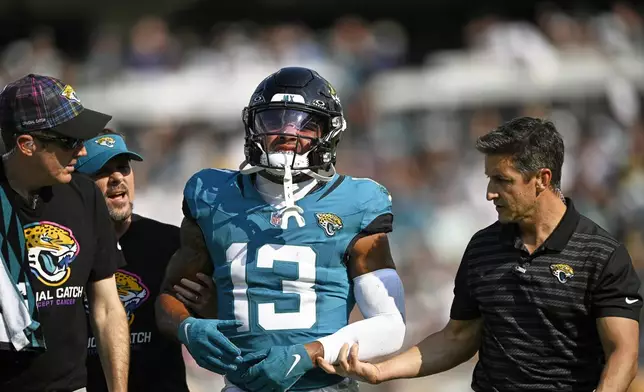 Jacksonville Jaguars' Christian Kirk is helped off the field during the second half of an NFL football game against the Green Bay Packers Sunday, Oct. 27, 2024, in Jacksonville, Fla. (AP Photo/Phelan M. Ebenhack)