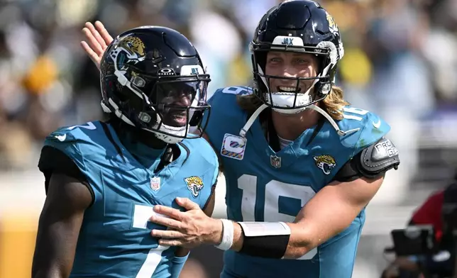 Jacksonville Jaguars' Trevor Lawrence congratulates Brian Thomas Jr. after a touchdown catch during the second half of an NFL football game against the Green Bay Packers Sunday, Oct. 27, 2024, in Jacksonville, Fla. (AP Photo/Phelan M. Ebenhack)