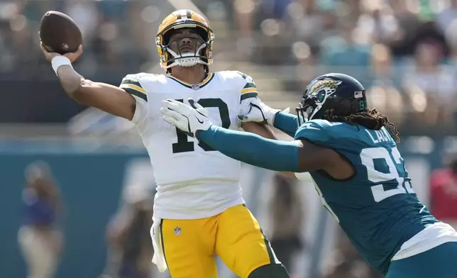 Green Bay Packers' Jordan Love throws while being hit by Jacksonville Jaguars' Tyler Lacy during the first half of an NFL football game Sunday, Oct. 27, 2024, in Jacksonville, Fla. (AP Photo/John Bazemore)