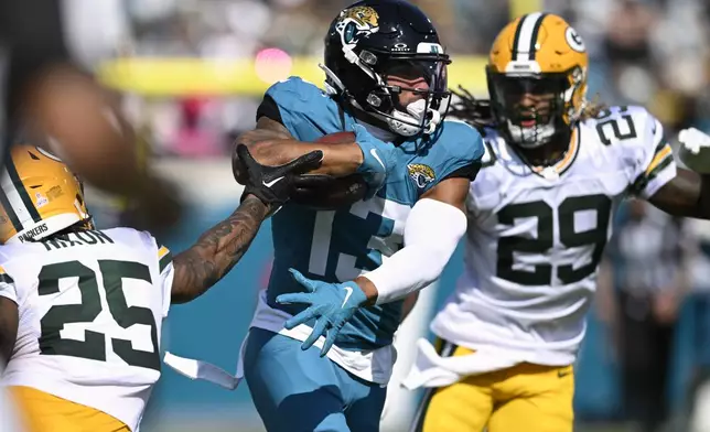 Jacksonville Jaguars' Christian Kirk runs past Green Bay Packers' Keisean Nixon (25) after a catch during the first half of an NFL football game Sunday, Oct. 27, 2024, in Jacksonville, Fla. (AP Photo/Phelan M. Ebenhack)