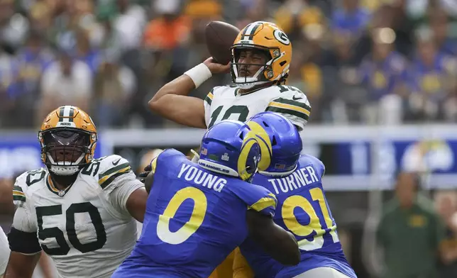 Green Bay Packers quarterback Jordan Love (10) is grabbed by Los Angeles Rams linebacker Byron Young (0) and defensive tackle Kobie Turner (91) during the first half of an NFL football game Sunday, Oct. 6, 2024, in Inglewood, Calif. (AP Photo/Ryan Sun)