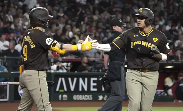 San Diego Padres' Manny Machado, right, celebrates with Jake Cronenworth (9) after scoring on a throwing error by Arizona Diamondbacks' Ketel Marte in the first inning during a baseball game, Friday, Sept. 27, 2024, in Phoenix. (AP Photo/Rick Scuteri)