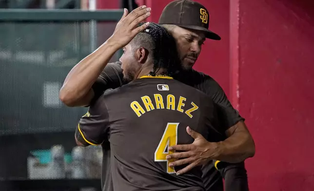 San Diego Padres' Luis Arraez (4) gets a hug in the dugout from teammate Xander Bogaerts, right, after hitting a double against the Arizona Diamondbacks during the sixth inning of a baseball game, Sunday, Sept. 29, 2024, in Phoenix. (AP Photo/Darryl Webb)