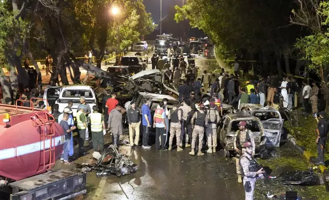 Security officials examine the site of an explosion that caused injures and destroyed vehicles at outside the Karachi airport, Pakistan, Monday, Oct. 7, 2024. (AP Photo/Fareed Khan)