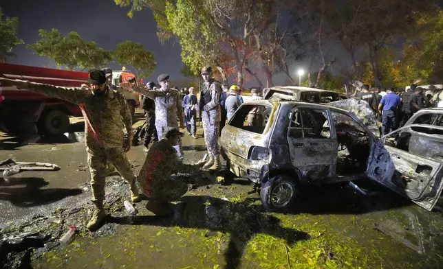 Security officials examine damage cars at the site of an explosion that caused injures and destroyed vehicles at outside the Karachi airport, Pakistan, Monday, Oct. 7, 2024. (AP Photo/Fareed Khan)