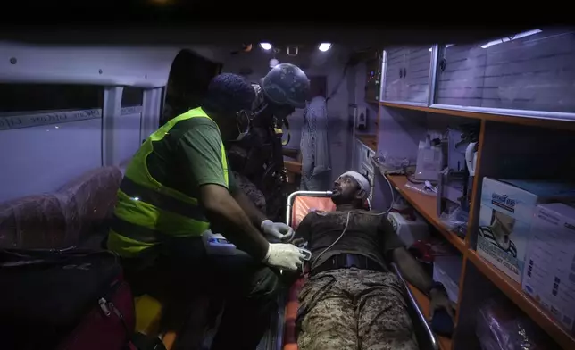 A Pakistani security official, who was injured in an explosion receives treatment inside an ambulance outside the Karachi airport, Pakistan, early Monday, Oct. 7, 2024. (AP Photo/Fareed Khan)