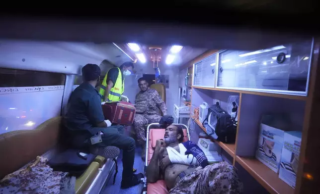 Pakistani security officials who were injured in an explosion receives treatment inside an ambulance outside the Karachi airport, Pakistan, Monday, Oct. 7, 2024. (AP Photo/Fareed Khan)