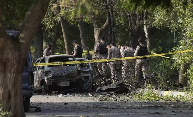 Security officials work on the site of an explosion that caused injures and destroyed vehicles outside the Karachi airport, Pakistan, Monday, Oct. 7, 2024. Pakistani Baloch separatists claim deadly bomb attack that killed 2 Chinese near Karachi airport. (AP Photo/Fareed Khan)