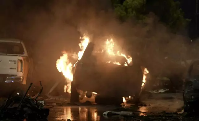 A vehicle is seen on fire at the site of an explosion that caused injures and destroyed vehicles at outside the Karachi airport, Pakistan, Sunday, Oct. 6, 2024. (AP Photo/Mohammad Farooq)