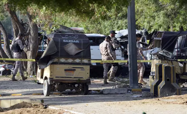 Security officials work on the site of an explosion that caused injures and destroyed vehicles outside the Karachi airport, Pakistan, Monday, Oct. 7, 2024. Pakistani Baloch separatists claim deadly bomb attack that killed 2 Chinese near Karachi airport. (AP Photo/Fareed Khan)