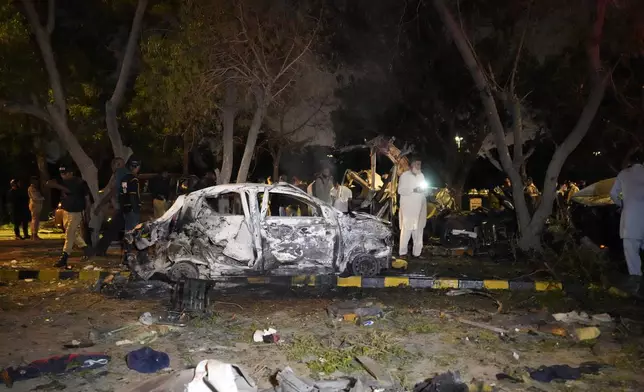 Security officials examine the site of an explosion that caused injures and destroyed vehicles outside the Karachi airport, Pakistan, early Monday, Oct. 7, 2024. (AP Photo/Fareed Khan)