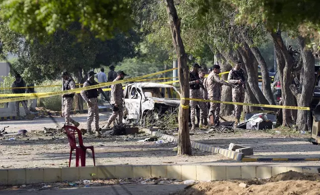 Security officials work on the site of an explosion that caused injures and destroyed vehicles outside the Karachi airport, Pakistan, Monday, Oct. 7, 2024. Pakistani Baloch separatists claim deadly bomb attack that killed 2 Chinese near Karachi airport. (AP Photo/Fareed Khan)