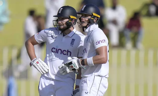 England's Gus Atkinson, left, and Jamie Smith look toward the big screen during the day one of third test cricket match between Pakistan and England, in Rawalpindi, Pakistan, Thursday, Oct. 24, 2024. (AP Photo/Anjum Naveed)