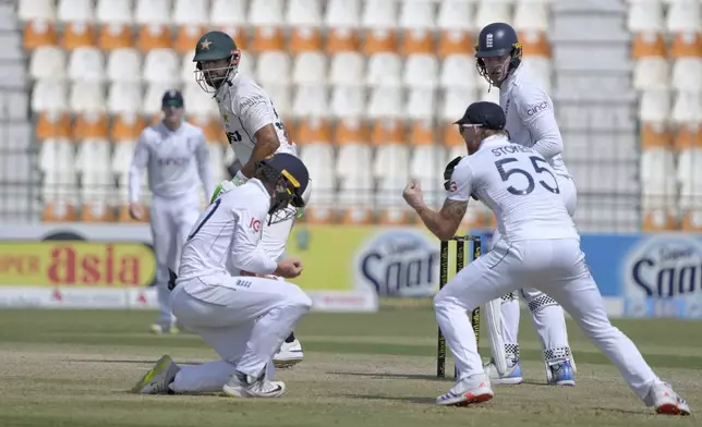 Pakistan's Shan Masood, second left, looks to England's Ollie Pope, left bottom, taking his catch to dismiss him during the third day of the second test cricket match between Pakistan and England, in Multan, Pakistan, Thursday, Oct. 17, 2024. (AP Photo/K.M. Chaudary)