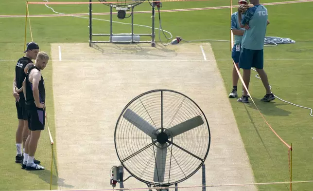 England's Brydon Carse, left, Olly Stone, second left, and Pakistan's coach Jason Gillespie, right, examine the pitch preparing for upcoming third test match between Pakistan and England, in Rawalpindi, Pakistan, Tuesday, Oct. 22, 2024. (AP Photo/Anjum Naveed)