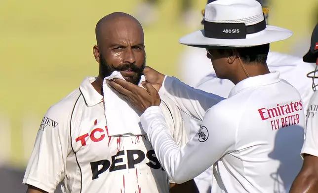 Umpire Sharfuddoula, right, helps to Pakistan's Sajid Khan, who injured when the ball hitting on his face during the day two of third test cricket match between Pakistan and England, in Rawalpindi, Pakistan, Friday, Oct. 25, 2024. (AP Photo/Anjum Naveed)