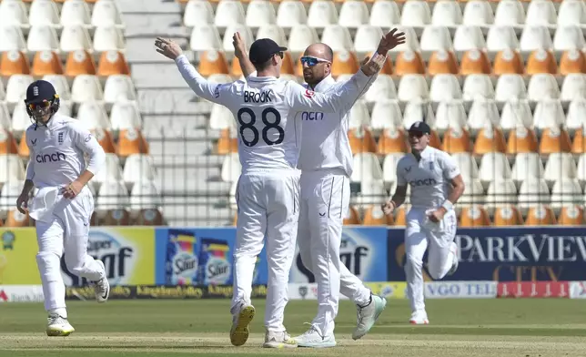 England's Jack Leach, second right, celebrates with teammate after taking the wicket of Pakistan's Abdullah Shafique during the first day of the second test cricket match between Pakistan and England, in Multan, Pakistan, Tuesday, Oct. 15, 2024. (AP Photo/K.M. Chaudary)