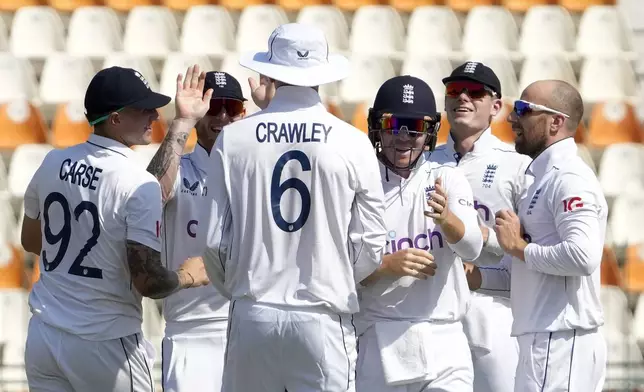 England's Jack Leach, right, celebrates with teammate after taking the wicket of Pakistan's Shan Masood during the first day of the second test cricket match between Pakistan and England, in Multan, Pakistan, Tuesday, Oct. 15, 2024. (AP Photo/K.M. Chaudary)