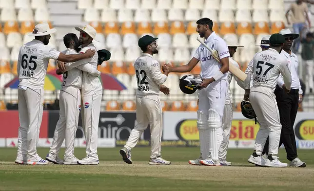 Pakistan's Kamran Ghulam, center, shakes hand with England's Shoaib Bashir, fifth right, as his teammate celebrate after winning the second test cricket match against England, in Multan, Pakistan, Friday, Oct. 18, 2024. (AP Photo/K.M. Chaudary)