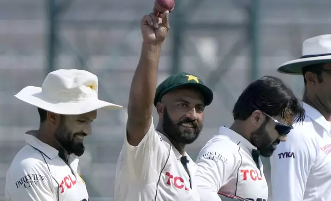 Pakistan's Sajid Khan, center, who took seven wickets, shows the ball as he walks off the field on end of England first innings during the third day of the second test cricket match between Pakistan and England, in Multan, Pakistan, Thursday, Oct. 17, 2024. (AP Photo/K.M. Chaudary)