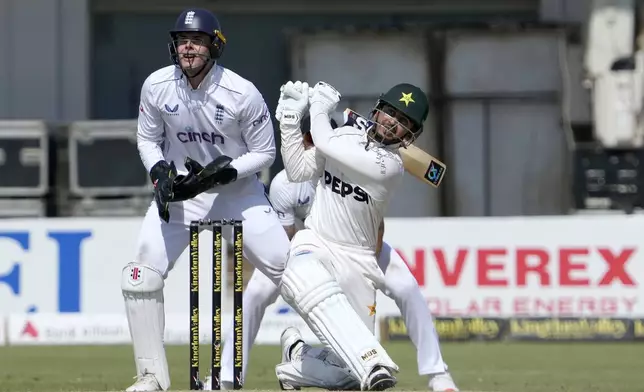 Pakistan's Saim Ayub, center, follows the ball after playing a shot as England's Jamie Smith watches during the first day of the second test cricket match between Pakistan and England, in Multan, Pakistan, Tuesday, Oct. 15, 2024. (AP Photo/K.M. Chaudary)