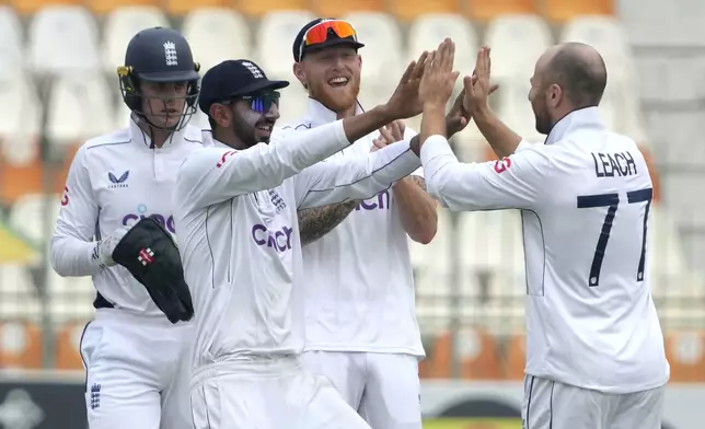 England's Jack Leach, right, celebrates with teammates after taking the wicket of Pakistan's Sajid Khan during the second day of the second test cricket match between Pakistan and England, in Multan, Pakistan, Wednesday, Oct. 16, 2024. (AP Photo/K.M. Chaudary)