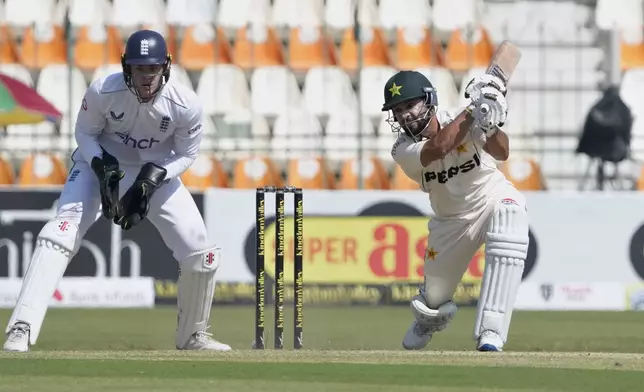 Pakistan's Kamran Ghulam, right, follows the ball after playing a shot as England's Jamie Smith watches during the first day of the second test cricket match between Pakistan and England, in Multan, Pakistan, Tuesday, Oct. 15, 2024. (AP Photo/K.M. Chaudary)