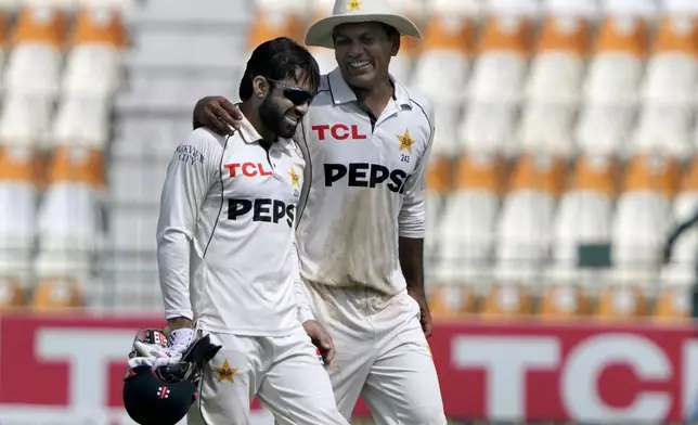 Pakistan's Noman Ali, right, chats with Mohammad Rizwan as they walk off the field after winning the second test cricket match against England, in Multan, Pakistan, Friday, Oct. 18, 2024. (AP Photo/K.M. Chaudary)