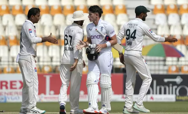 Pakistan's Noman Ali, left, shakes hand with England's Matthew Potts, center, after winning the second test cricket match against England, in Multan, Pakistan, Friday, Oct. 18, 2024. (AP Photo/K.M. Chaudary)