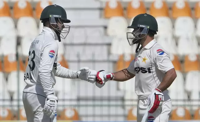 Pakistan's Kamran Ghulam, right, and Saim Ayub bumps their fists during the first day of the second test cricket match between Pakistan and England, in Multan, Pakistan, Tuesday, Oct. 15, 2024. (AP Photo/K.M. Chaudary)