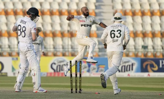 England's Harry Brook, left, looks to wickets after he is bowled out by Pakistan's Sajid Khan, center, during the second day of the second test cricket match between Pakistan and England, in Multan, Pakistan, Wednesday, Oct. 16, 2024. (AP Photo/K.M. Chaudary)