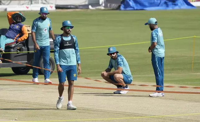 Pakistan's Saud Shakeel, right, with teammates examine pitch preparing for second test cricket match against England after a practice session, in Multan, Pakistan, Monday, Oct. 14, 2024. (AP Photo/K.M. Chaudary)