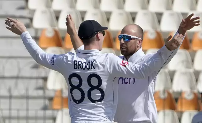 England's Jack Leach, right, celebrates with teammate after taking the wicket of Pakistan's Abdullah Shafique during the first day of the second test cricket match between Pakistan and England, in Multan, Pakistan, Tuesday, Oct. 15, 2024. (AP Photo/K.M. Chaudary)