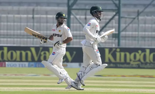 Pakistan's Kamran Ghulam, left, and Saim Ayub run between the wickets during the first day of the second test cricket match between Pakistan and England, in Multan, Pakistan, Tuesday, Oct. 15, 2024. (AP Photo/K.M. Chaudary)