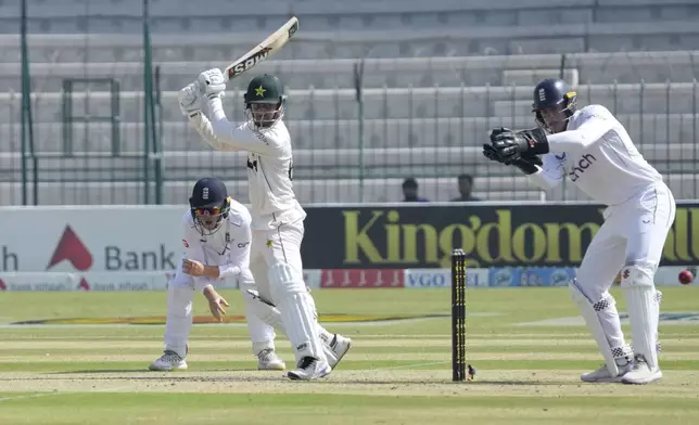 Pakistan's Saim Ayub, second left, plays a shot as England's Jamie Smith, right, and Ollie Pope watch during the first day of the second test cricket match between Pakistan and England, in Multan, Pakistan, Tuesday, Oct. 15, 2024. (AP Photo/K.M. Chaudary)