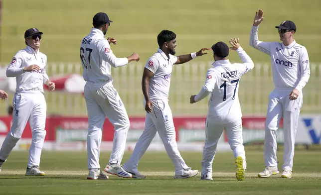 England's Rehan Ahmed, center, celebrates with teammates after taking the wicket of Pakistan's Aamer Jamal during the day two of third test cricket match between Pakistan and England, in Rawalpindi, Pakistan, Friday, Oct. 25, 2024. (AP Photo/Anjum Naveed)