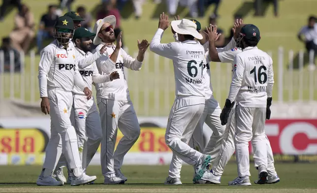 Pakistan's Salman Ali Agha, center, celebrates with teammates after taking the catch of England's Ben Stokes during the day one of third test cricket match between Pakistan and England, in Rawalpindi, Pakistan, Thursday, Oct. 24, 2024. (AP Photo/Anjum Naveed)