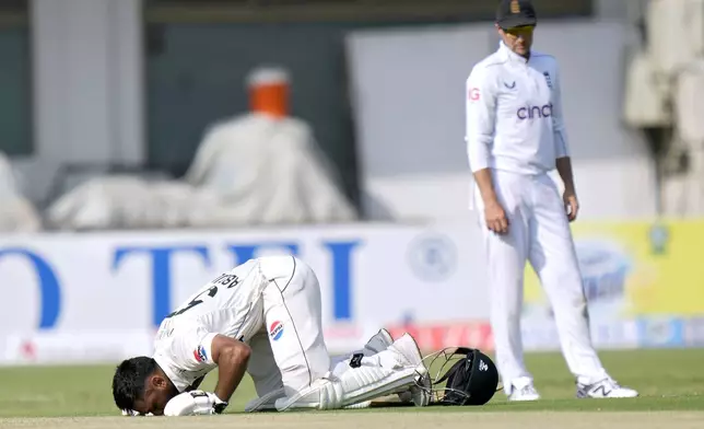 Pakistan's Abdullah Shafique, bottom, performs Sajdah, a prayer bow in gratitude to God, after scoring century as England's Joe Root watches during the first day of the first test cricket match between Pakistan and England, in Multan, Pakistan, Monday, Oct. 7, 2024. (AP Photo/Anjum Naveed)